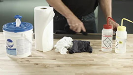 Video still showing cleaning supplies: disposable towels, cloth wipes and bottles of acetone and isopropyl alcohol