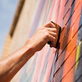 Hand using tool to install printed graphic film to brick wall