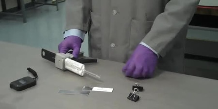 A lab worker prepares to apply adhesive to metal strips for a strength test
