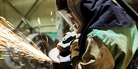 Worker grinding metal with safety face shield and hood
