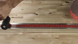 Video still of a person using a J-roller to ensure even pressure is applied to the tape