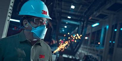 worker wearing 3M disposable respirator and hard hat
