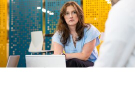 Woman in an office speaking to another coworker.